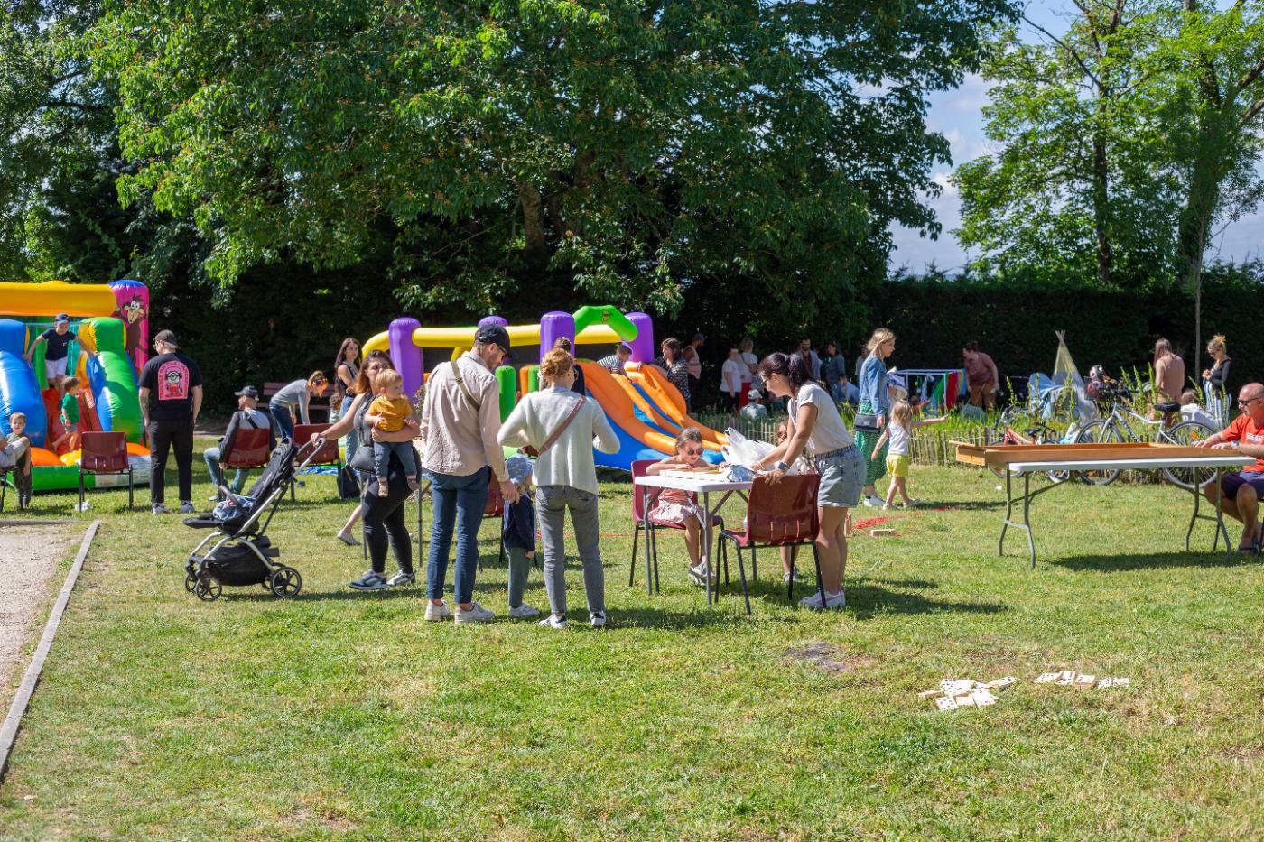 Familles réunies autour des jeux et structures gonflables lors d’une fête du Temps des Familles dans un parc