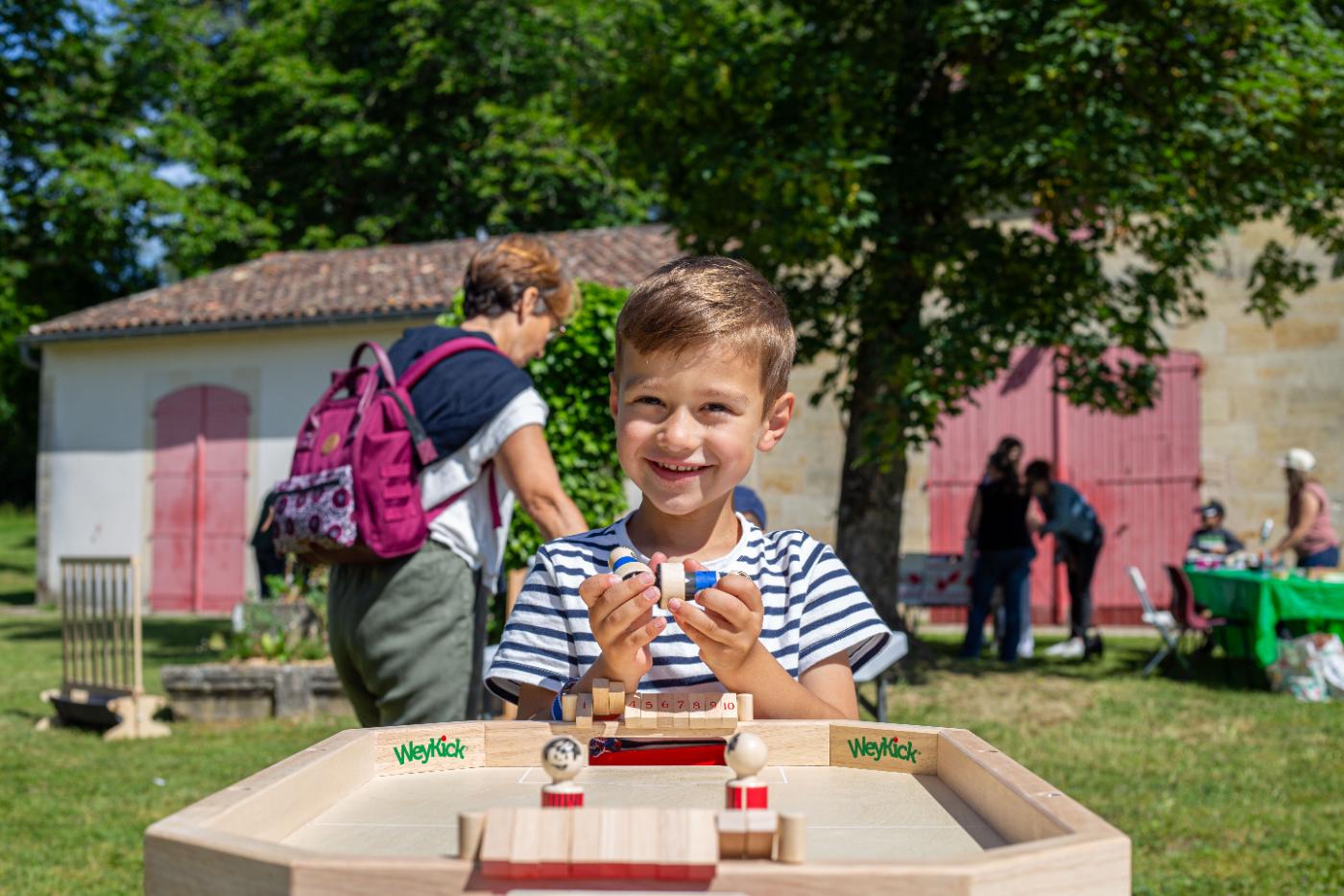 Un enfant souriant joue à un jeu en bois lors d’un après-midi festif de l’association