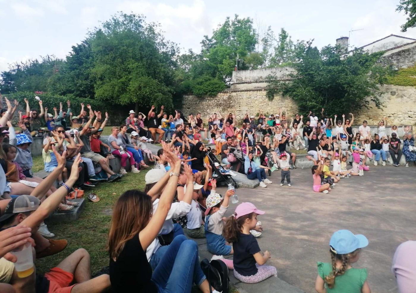 Un large public de familles assiste à un spectacle en plein air organisé par Le Temps des Familles