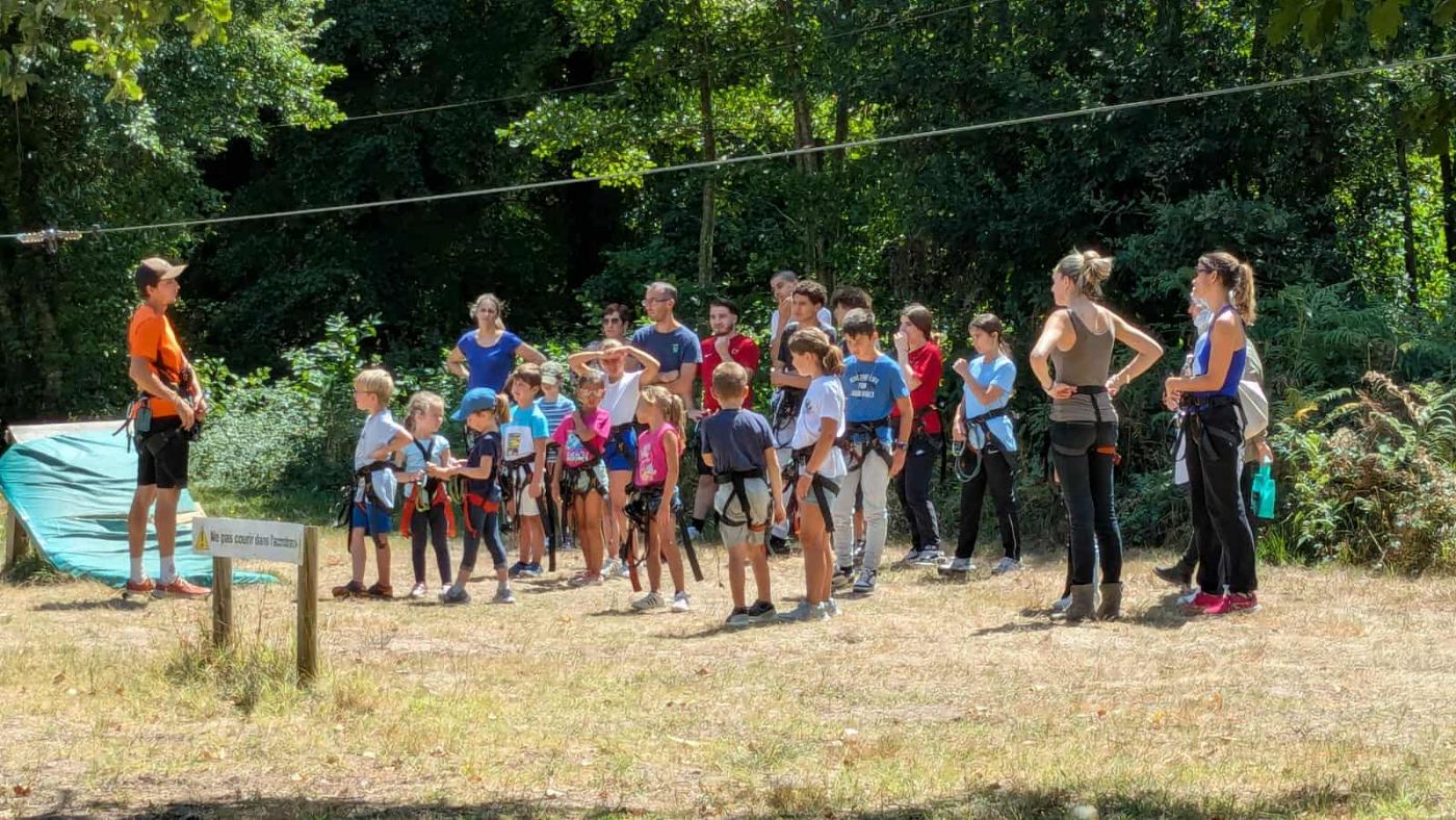 Sortie accrobranche du Temps des Familles : enfants et parents équipés écoutent le moniteur